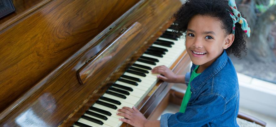Boy playing wood finish grand piano saying"Practice regularly."